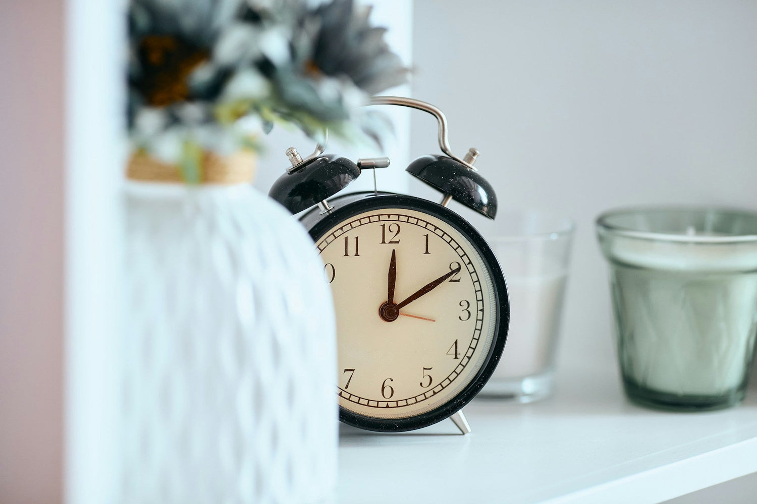 Stylish-bedroom-with-decorative-analog-and-LED-alarm-clocks-on-bedside-table